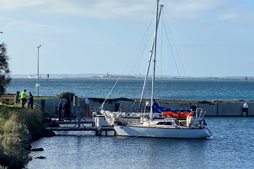 Two yachts side-by-side at a jetty with a tarp across the front of the one furthest away.