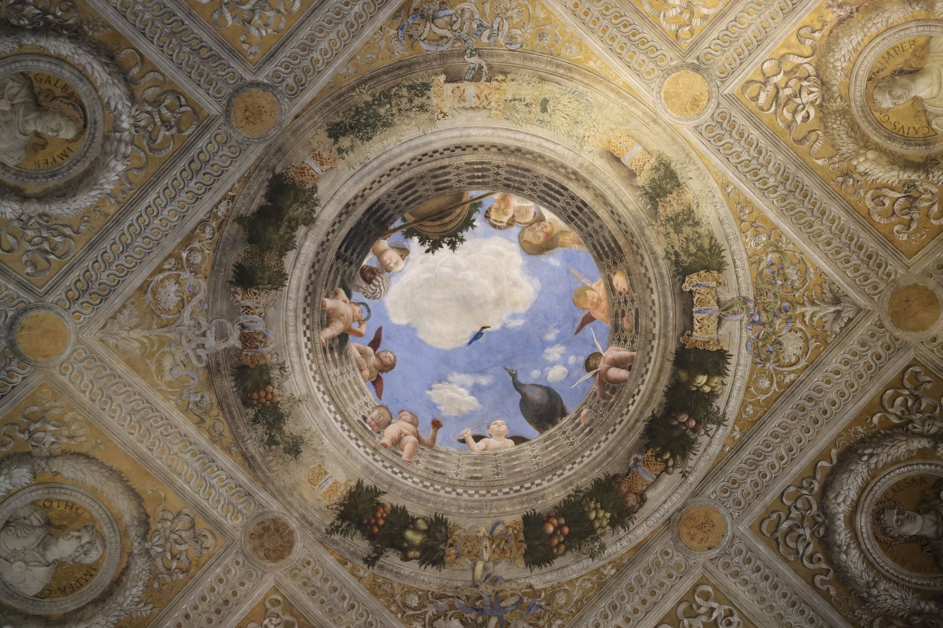 An elaborately painted ceiling with cherubs surrounding an aperture with blue sky beyond