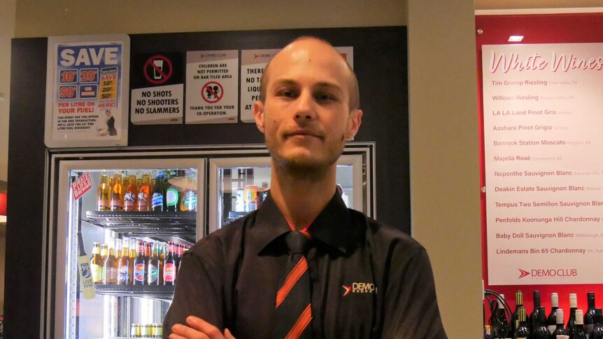 Demo Club Bar Supervisor Joshua Tracey stands cross-armed behind the club's main bar