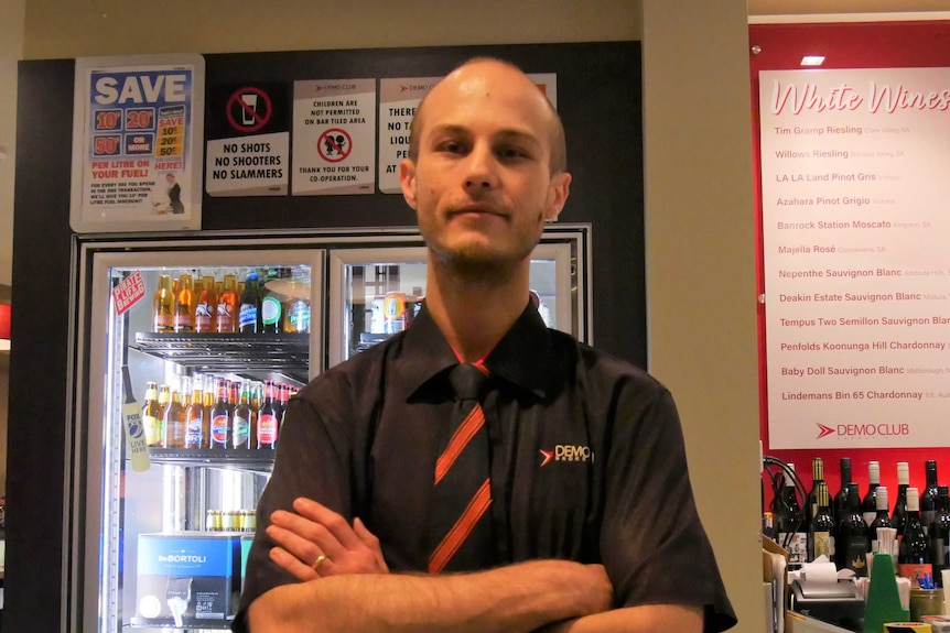 Demo Club Bar Supervisor Joshua Tracey stands cross-armed behind the club's main bar