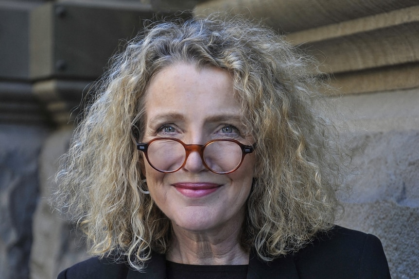 Delia Rickard stands in front of a building.