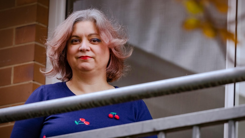 A woman in a blue top standing at a balcony 