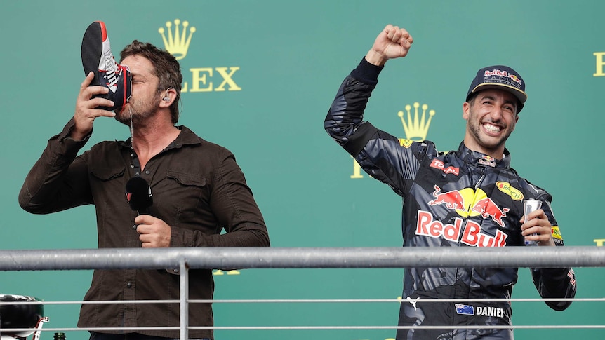 Gerard Butler does a 'shoey' as Daniel Ricciardo smiles along