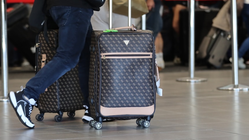 A person walking through Brisbane Airport with a suitcase on wheels
