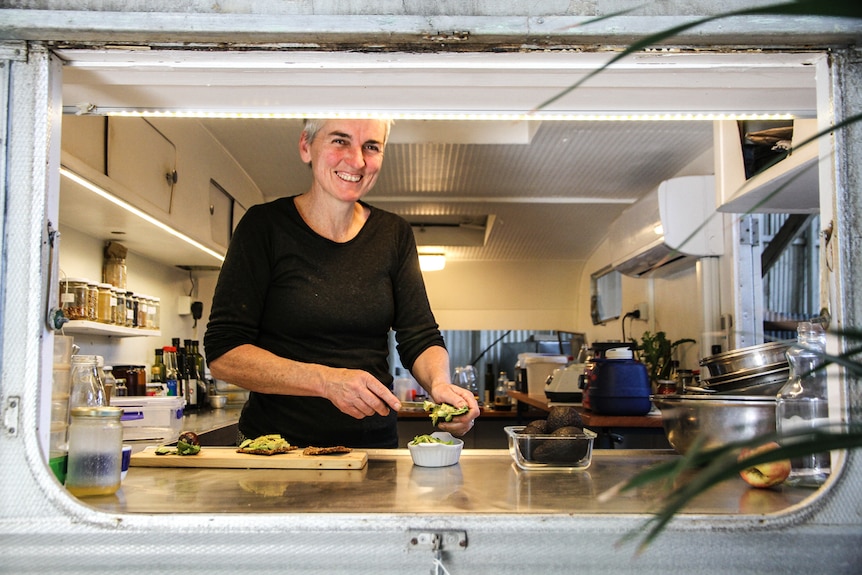 Caithlin Meave in her caravan cafe dishing up some avocado on homemade vegan crackers.