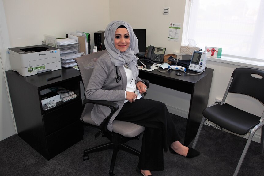 Woman in a headscarf sitting at a desk.