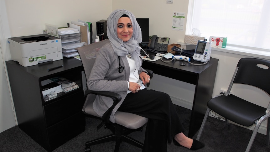Woman in a headscarf sitting at a desk.