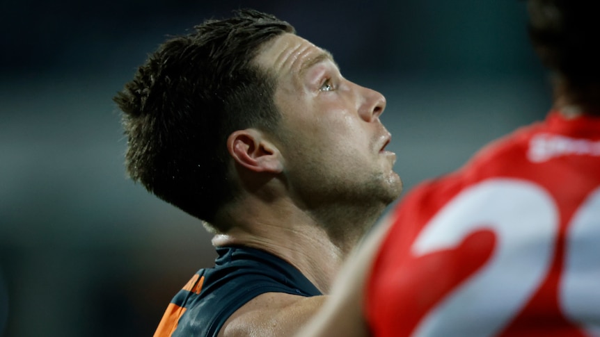 An AFL player looks away and up at the sky during a finals game.