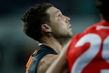 An AFL player looks away and up at the sky during a finals game.