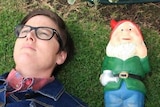 Hannah Gadsby on the grass next to a gnome
