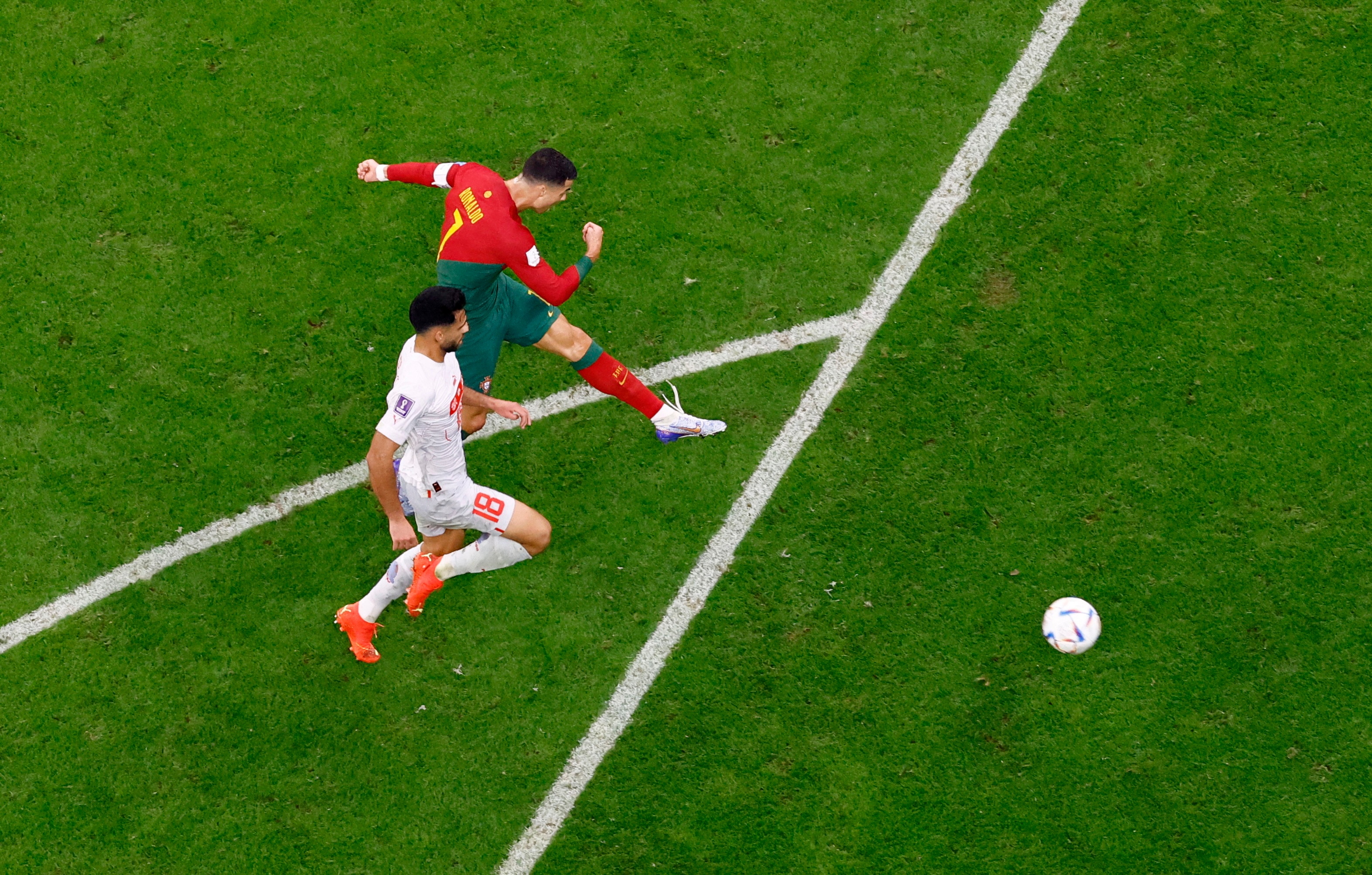 Cristiano Ronaldo kicks a ball slightly in front of a Switzerland player at his side.