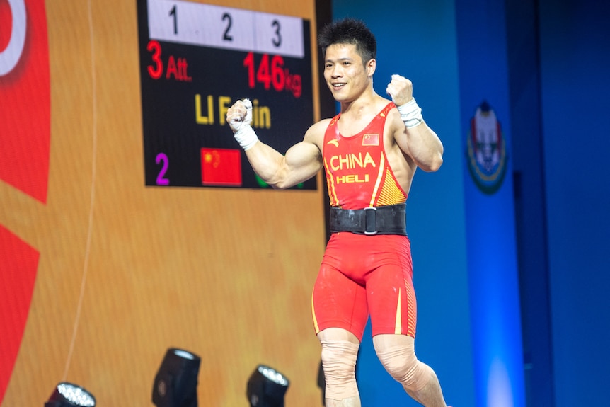 A weightlifter in the red competition outfit of Chinese athletes celebrates after breaking the world record with 146kg in snatch