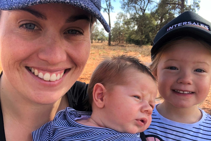 A selfie of a smiling woman, her baby son and young daughter.