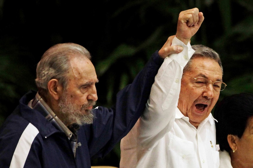 fidel castro holds up the arm of raul castro