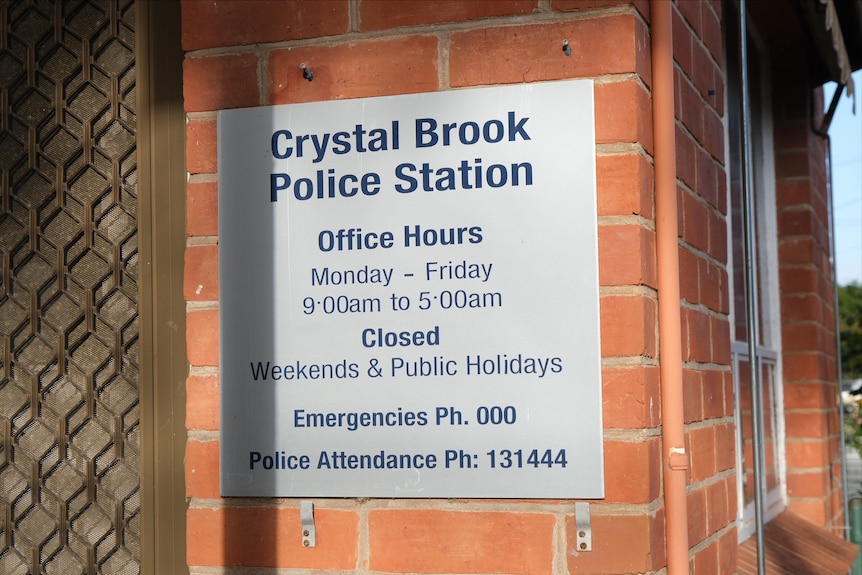 A sign on the red-brick facade of a police station.
