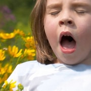 A girl sneezing holding flowers in her hand