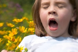 A girl sneezing holding flowers in her hand