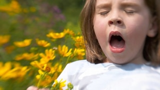 A girl sneezing holding flowers in her hand