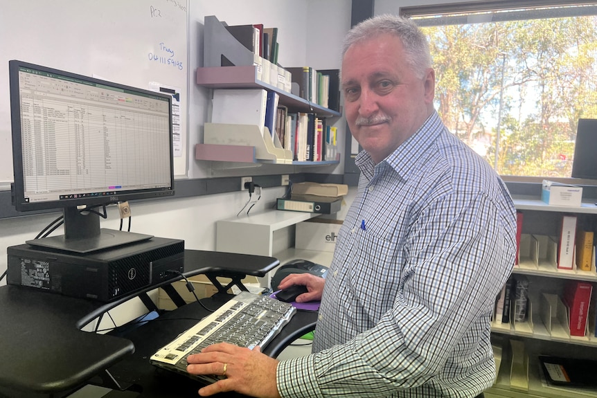 Dr Russell Stafford stands at a computer