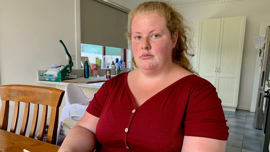 Sexual abuse survivor Keelie McMahon sits in her kitchen holding an iPad.