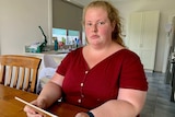 Sexual abuse survivor Keelie McMahon sits in her kitchen holding an iPad.