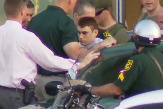 A young man is surrounded by police officers.