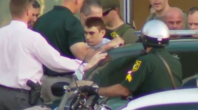 A young man is surrounded by police officers.