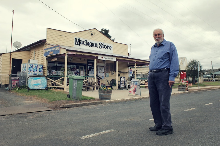 A man stands in front of an old shop