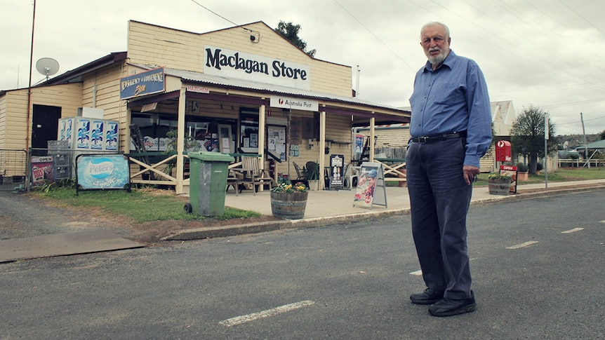 A man stands in front of an old shop