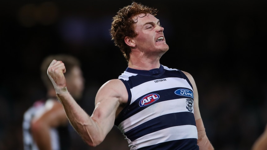 A Geelong AFL pumps his right fist as he celebrates kicking a goal.