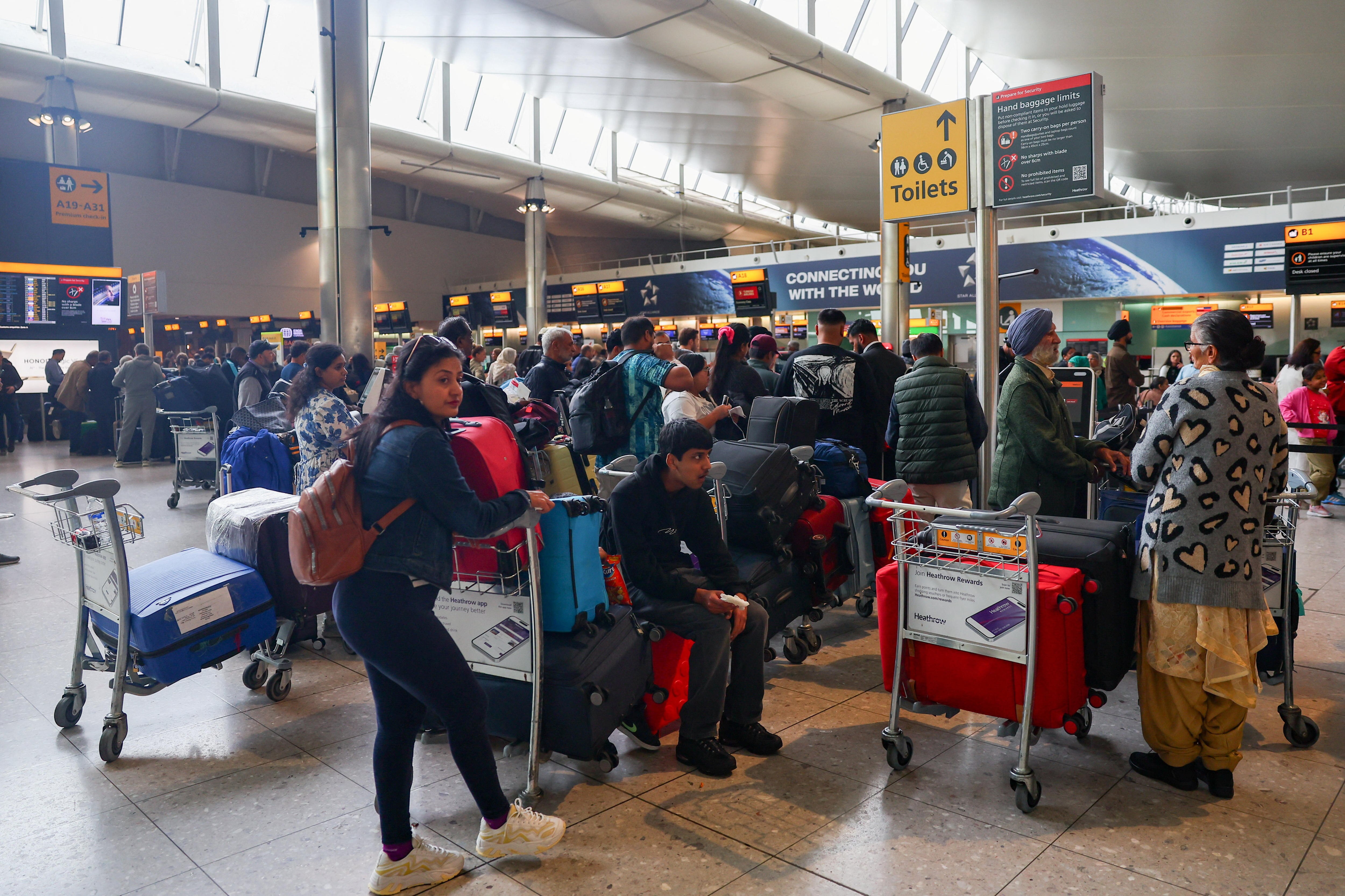 Travellers wait near check-in desks at Heathrow Airport Terminal 2