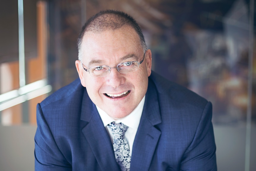 Grant Johnston wears a suit and smiles at the camera