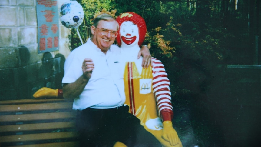 Vincent Ryan holds a balloon and poses for a photo with a statue of Ronald McDonald.