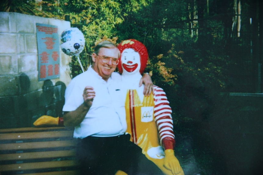 Vincent Ryan holds a balloon and poses for a photo with a statue of Ronald McDonald.