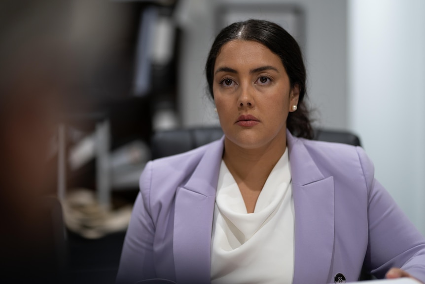 A well dressed woman stares ahead as she looks toward a camera