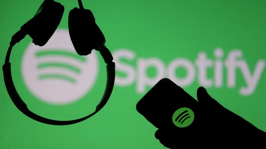 A person's hand holding a mobile phone, showing the Spotify logo.