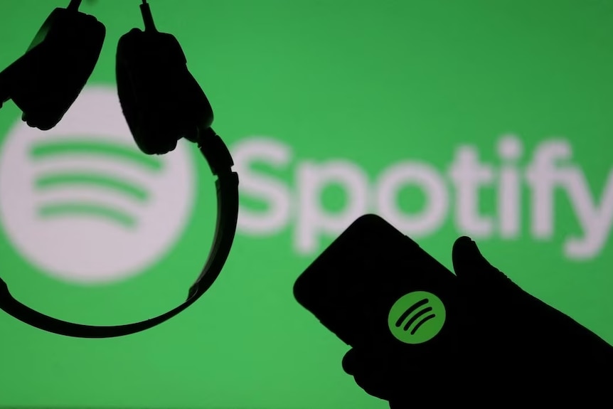 A person's hand holding a mobile phone, showing the Spotify logo.