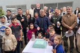 A bunch of Yazidi familes cut a celebration cake 