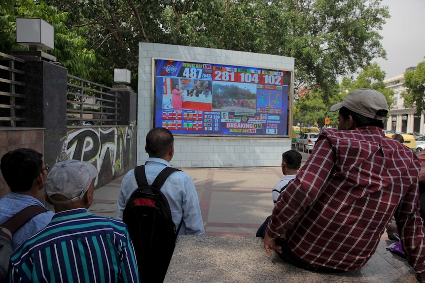 Indians watch early trends on a screen as counting of votes.