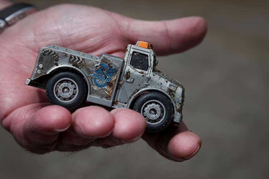 A man's hand holds a toy truck.