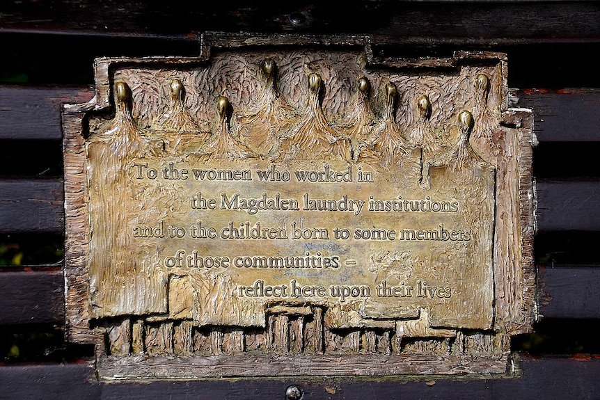 Close up of gold plaque: 'To the women who worked in the Magdalen laundry institutions...reflect here upon their lives.'