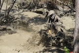 A quad bike rider covered in mud
