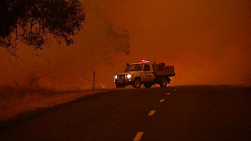 An emergency services vehicle sits by the side of a road in Gippsland as bushfires rage.