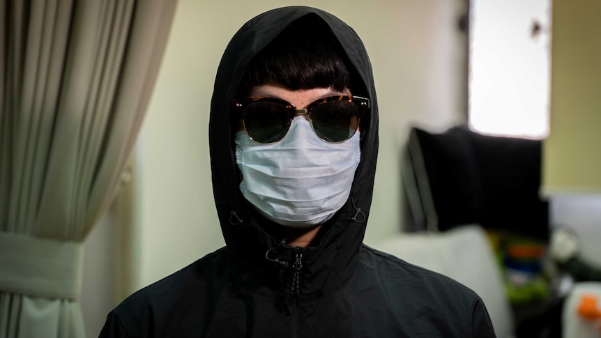 A boy in a hoodie, sunglasses and a face mask