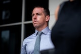 a young man wearing a blue collared shirt outside court