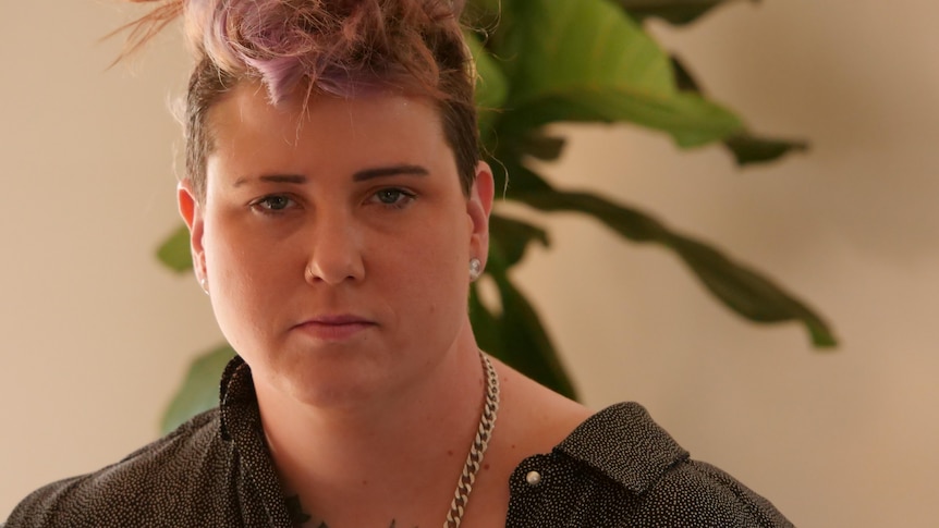 a woman with short pink hair wearing a black shirt.