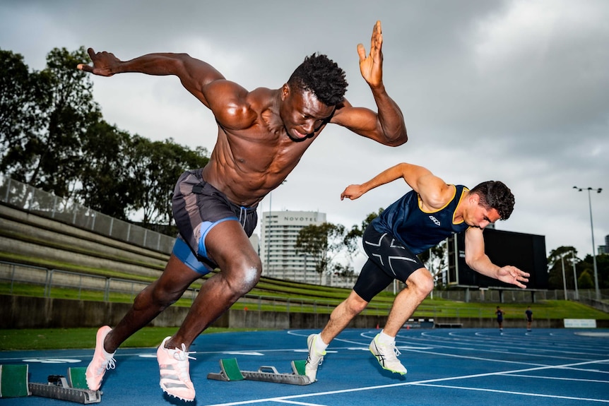 Two sprinters burst from their marks in a sprint on an athletics track