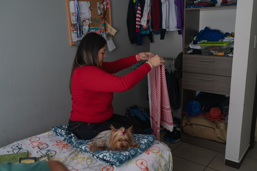 A woman folds a head scarf.