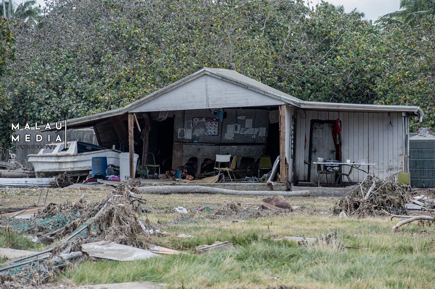 boat sits next to house in ruins after Tonga's volcanic eruption. 