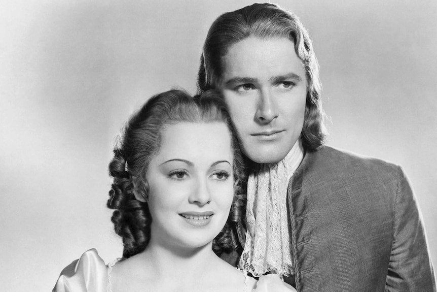 A black and white photograph shows two actors in costume posing